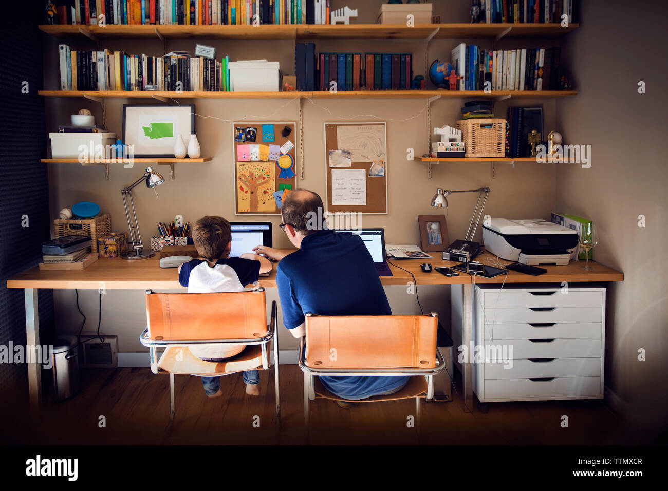 Father assisting son in using laptop computer at home Stock Photo