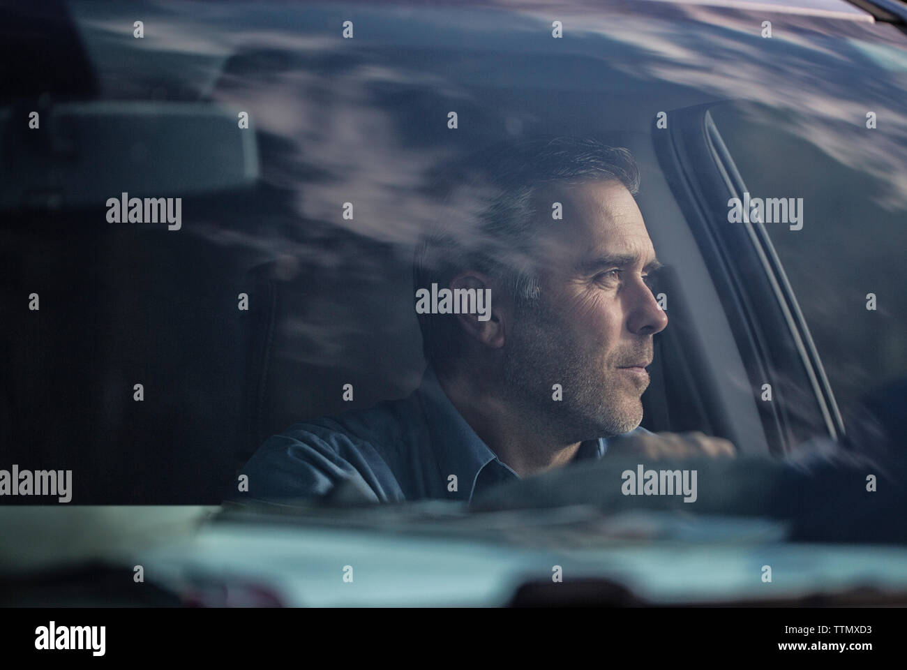 Man looking away while sitting in car seen through windshield Stock Photo