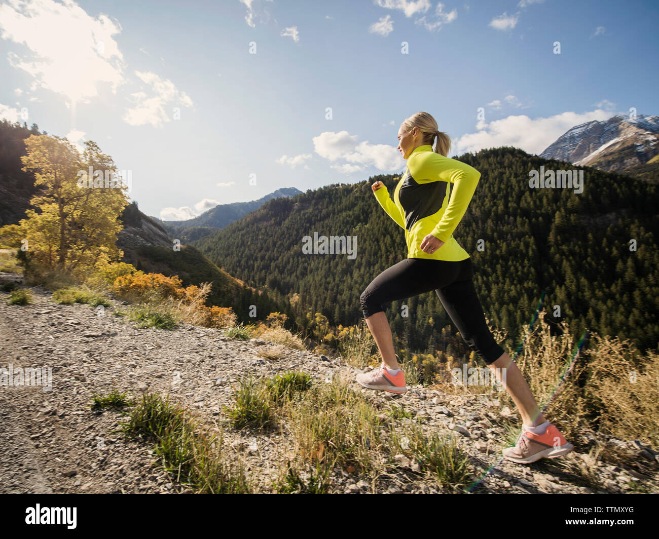 Healthy Caucasian woman running on mountain trail in autumn Stock Photo