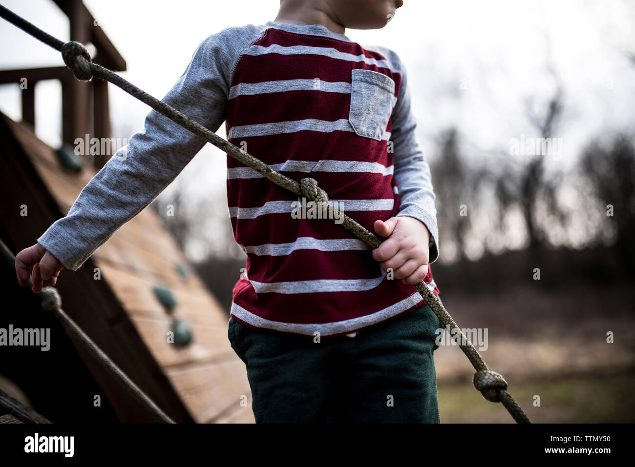 Midsection of boy holding rope at playground Stock Photo
