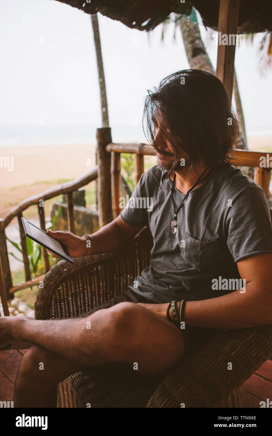 Man using tablet computer while sitting at beach Stock Photo