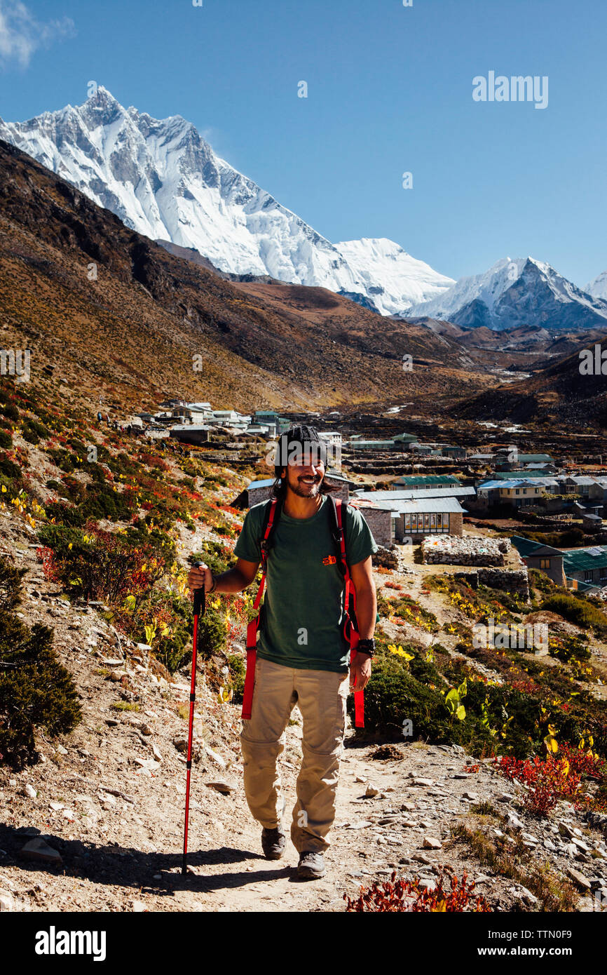 Male hiker with hiking pole walking on mountain against blue sky at Sagarmatha National Park Stock Photo