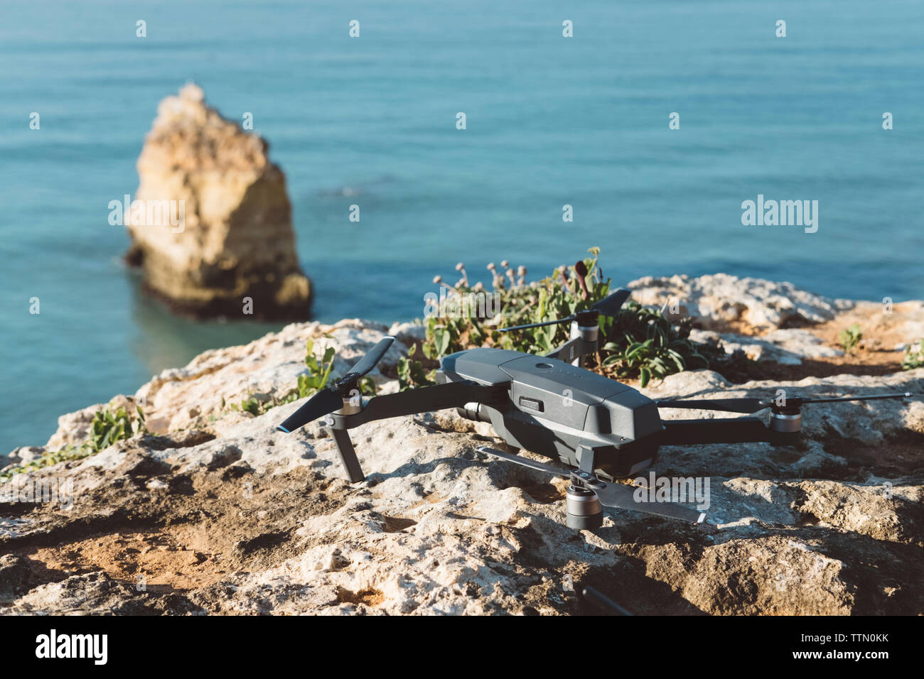 High angle view of quadcopter on rock formation at beach during sunset Stock Photo