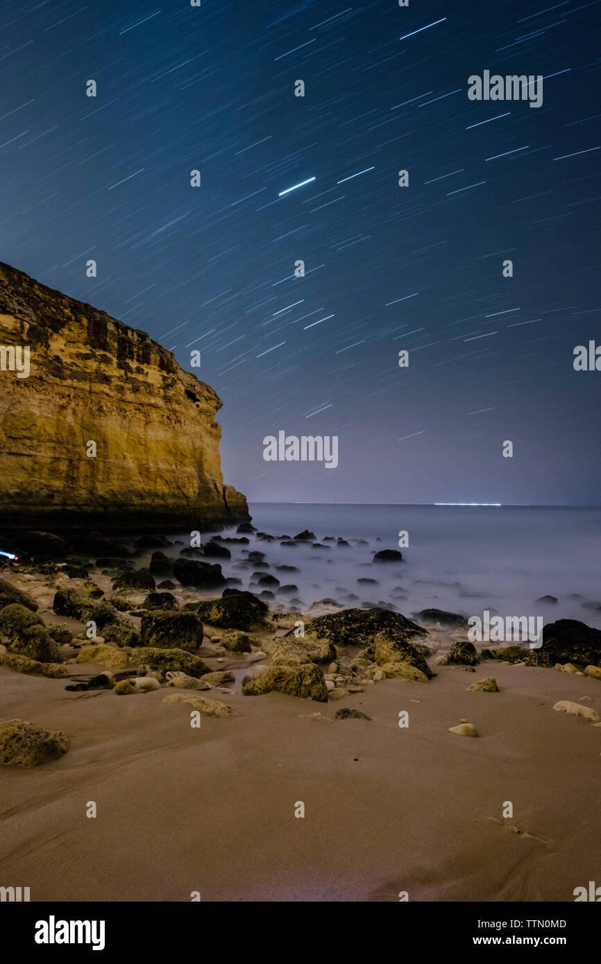 Scenic view of sea against star trails at night Stock Photo