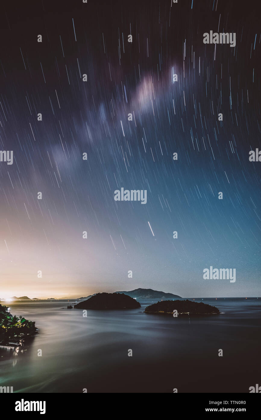 Scenic view of sea against star trails at night Stock Photo