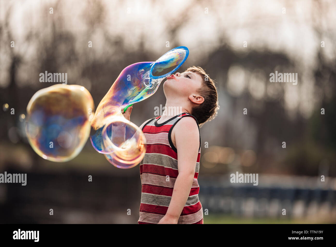 Boy blowing bubbles while playing at park Stock Photo