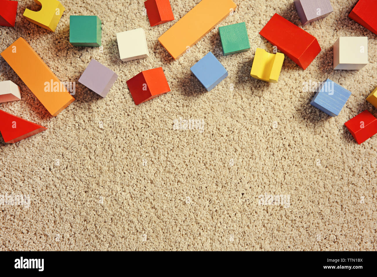 Colorful wooden building blocks for children on carpet, top view Stock Photo