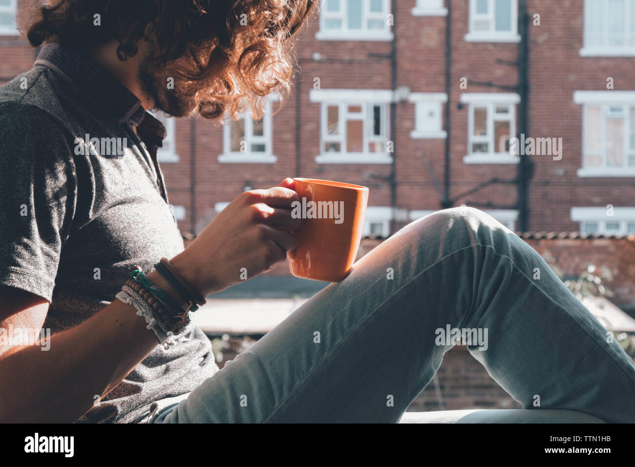 Person having a coffee on an orange mug outside Stock Photo