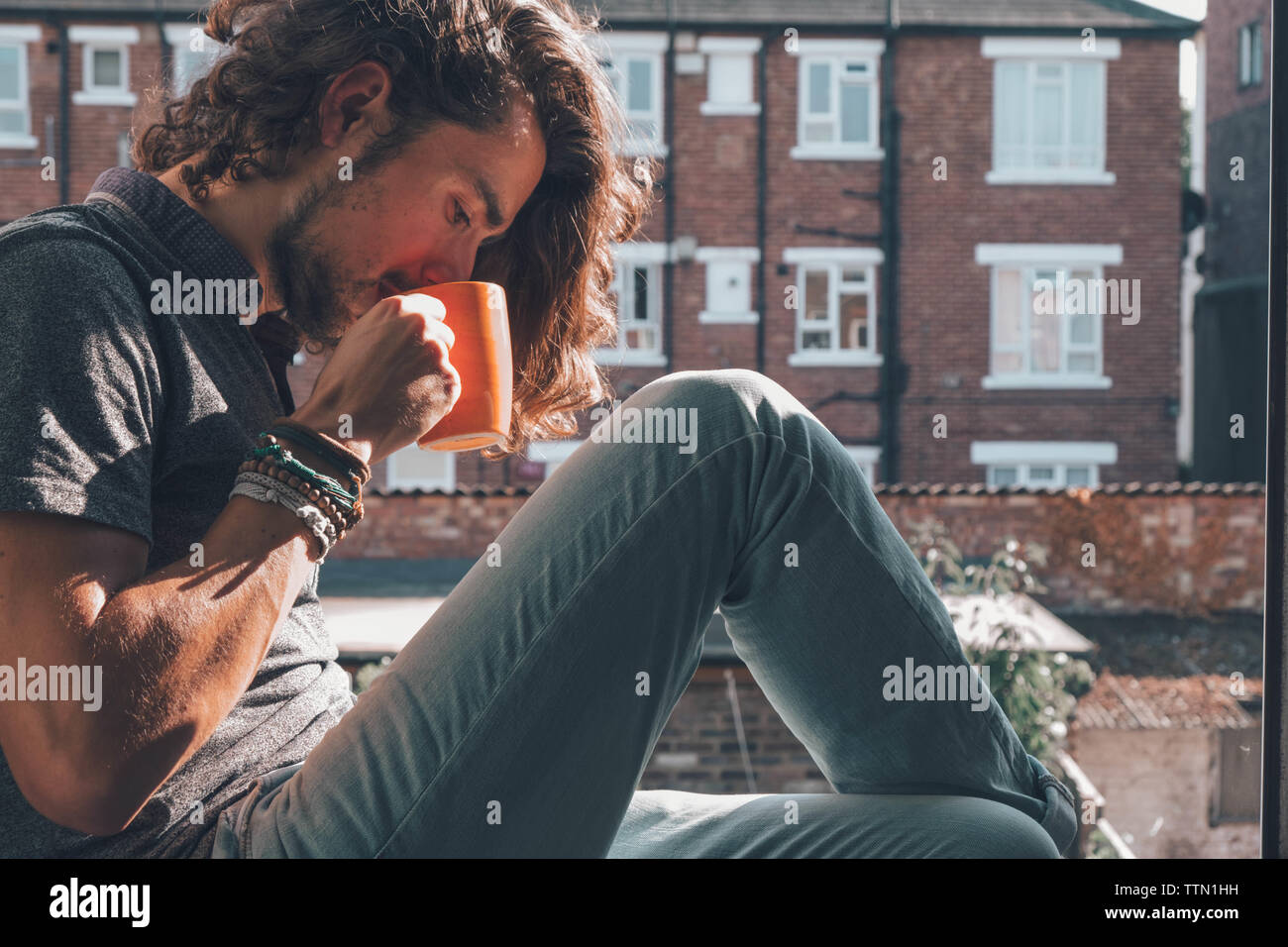 Person having a coffee on an orange mug outside Stock Photo