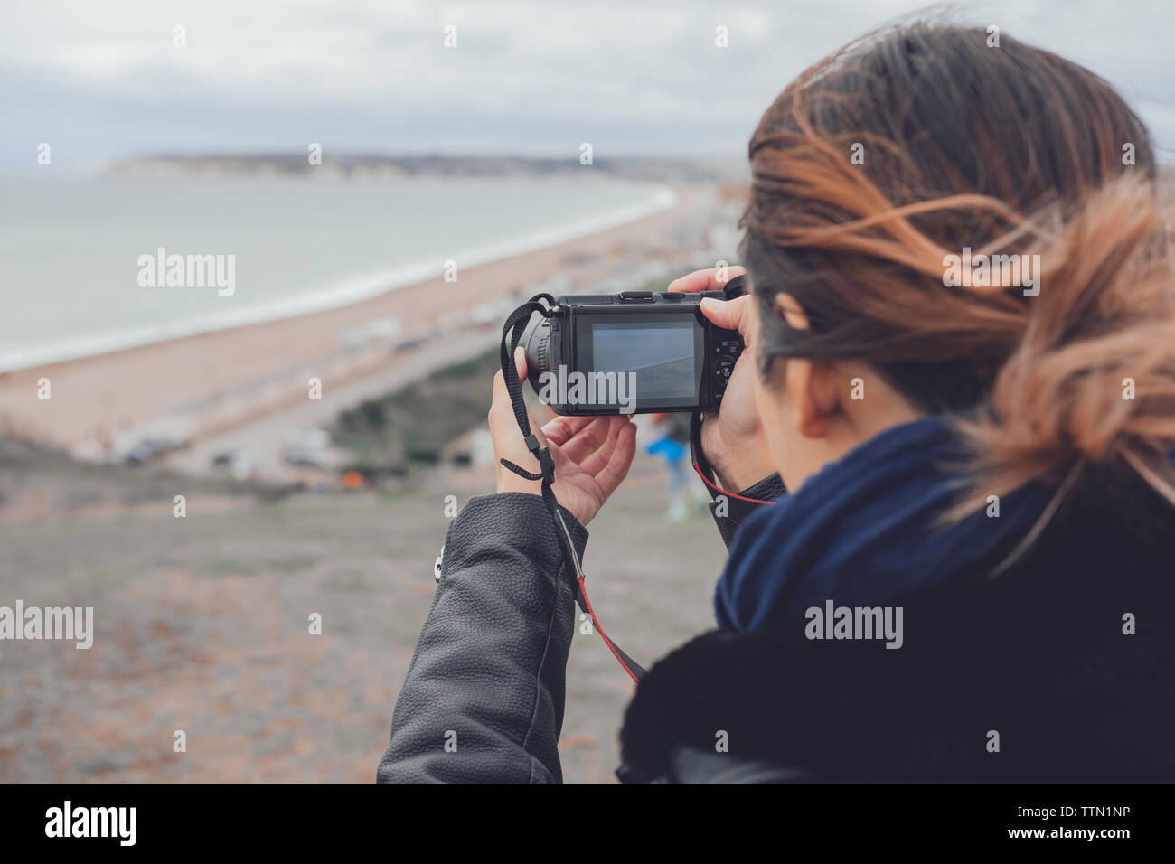 Woman taking photos on a cliff by the sea in autumn Stock Photo
