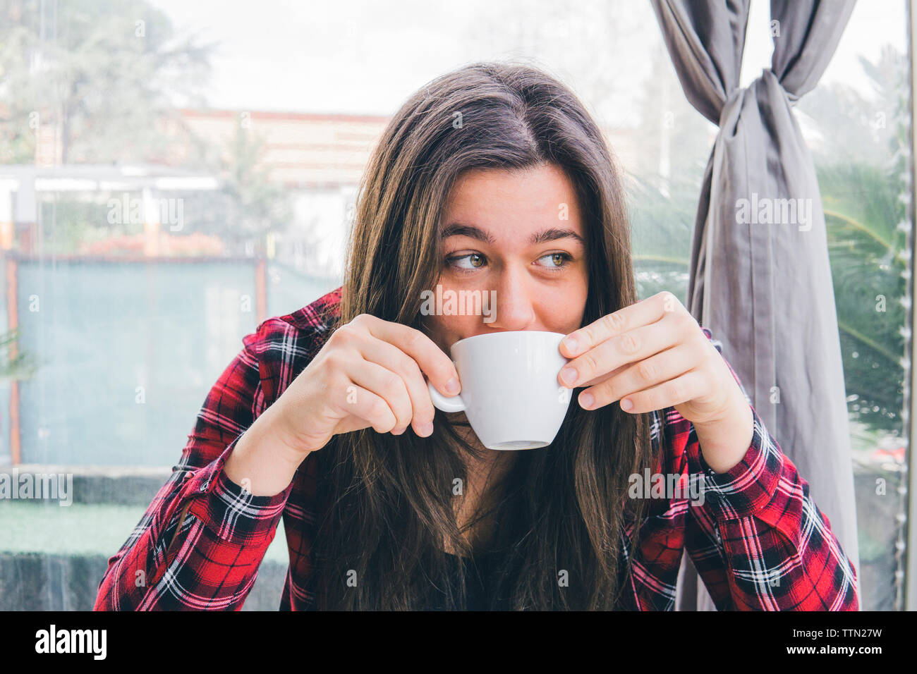 Woman looking away while drinking coffee in cafe Stock Photo