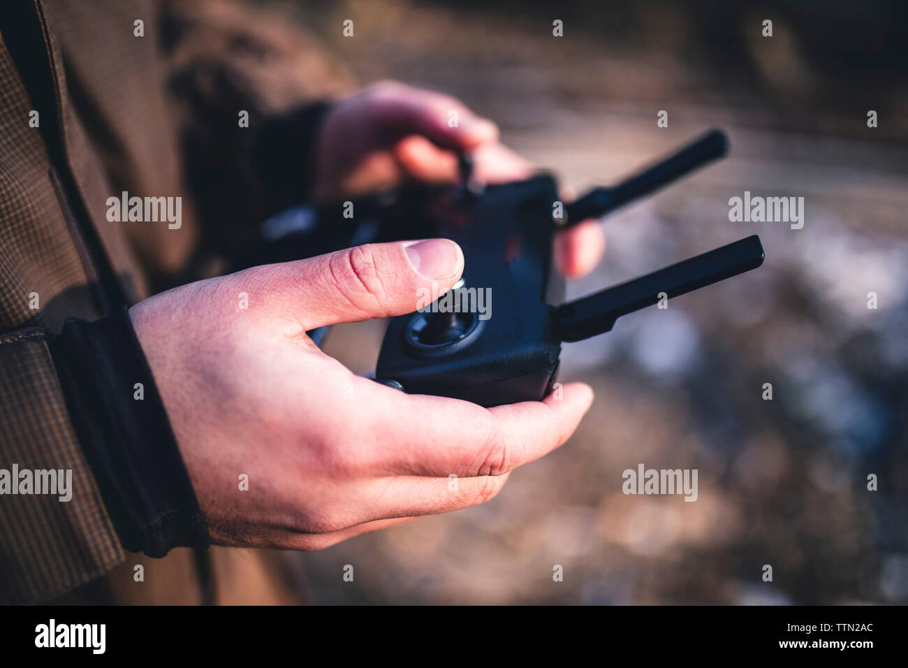 Midsection of male hiker operating remote control while standing in forest Stock Photo