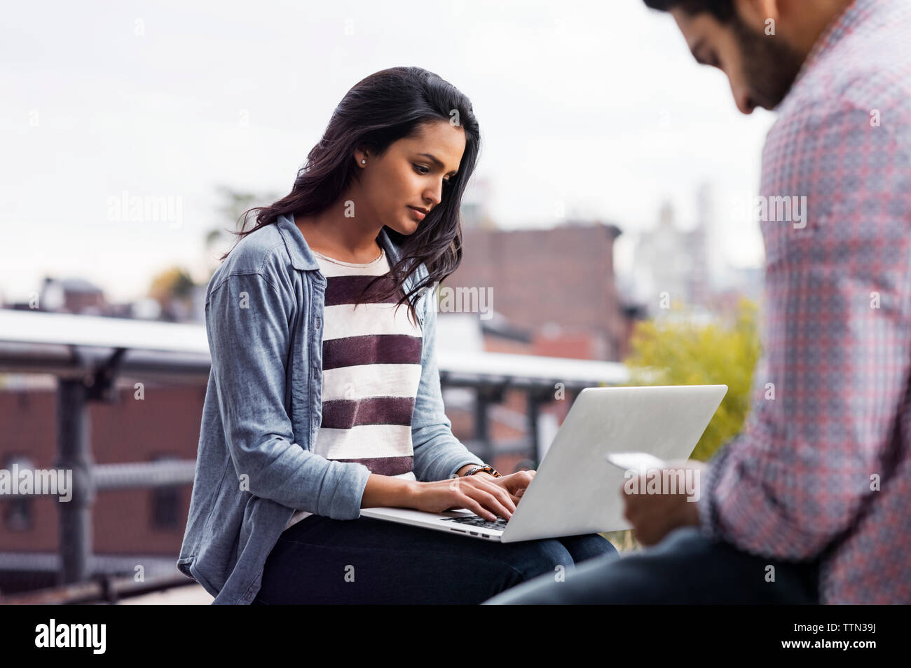 Woman using laptop on rooftop Stock Photo