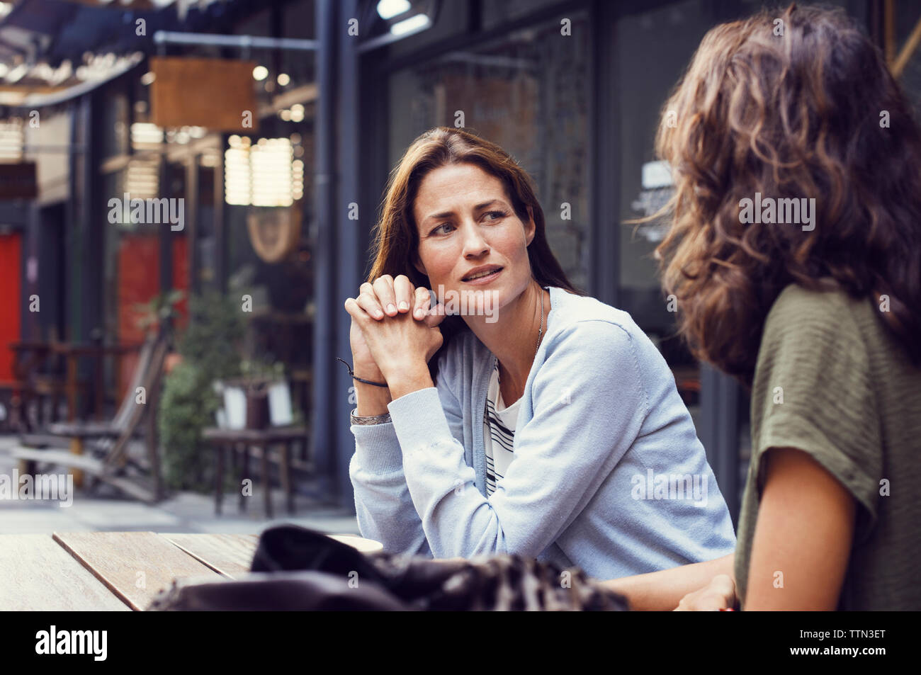 Mature woman talking to friend at sidewalk cafe Stock Photo