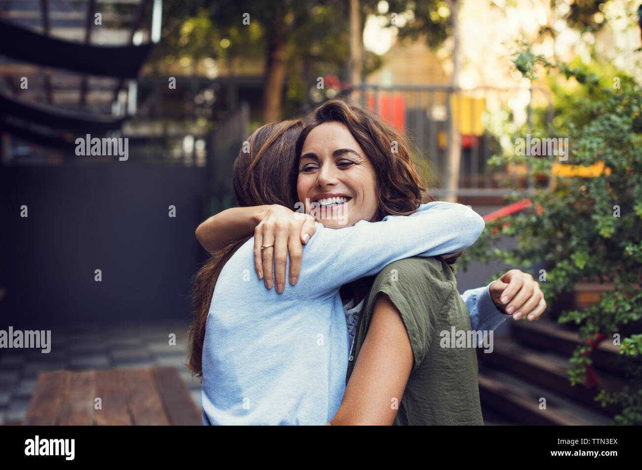 Affectionate mature women embracing at sidewalk cafe Stock Photo