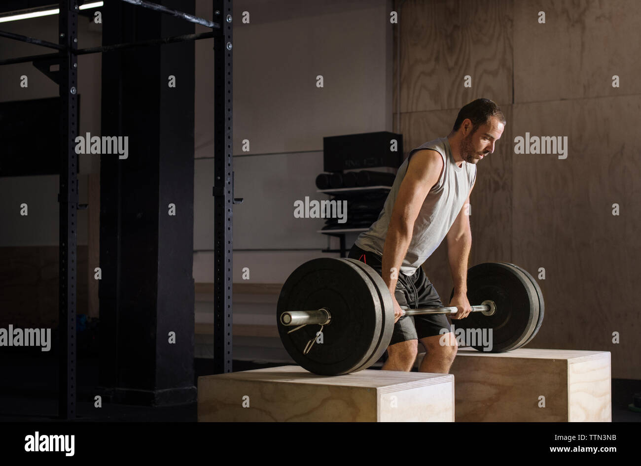Determined male athlete lifting barbell in gym Stock Photo