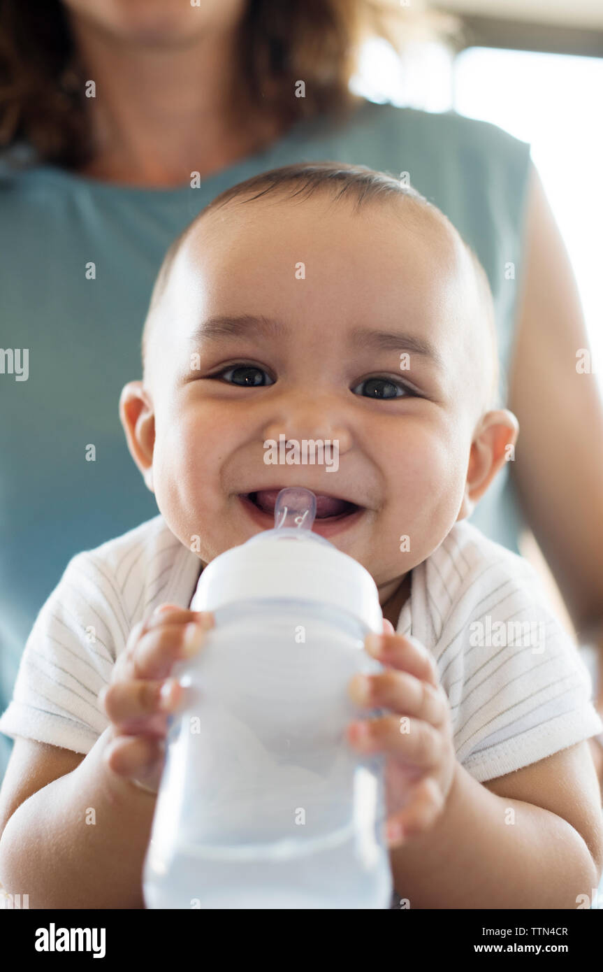 https://c8.alamy.com/comp/TTN4CR/portrait-of-smiling-baby-boy-holding-bottle-while-sitting-with-mother-TTN4CR.jpg