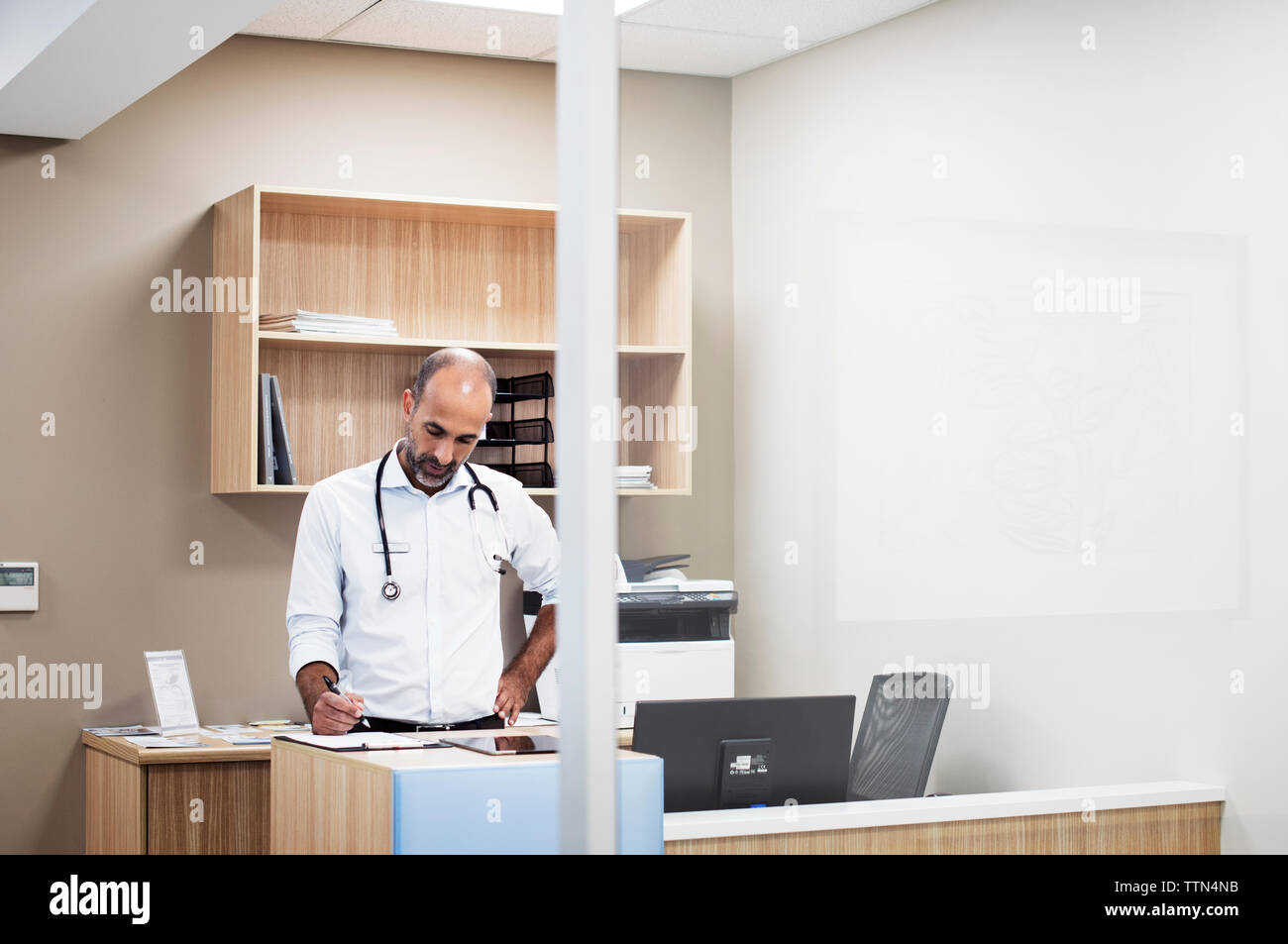 Doctor with hand on hip working while standing in room at hospital Stock Photo