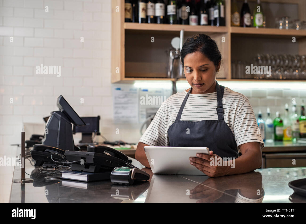 Confident female owner using tablet computer on bar counter in cafeteria Stock Photo