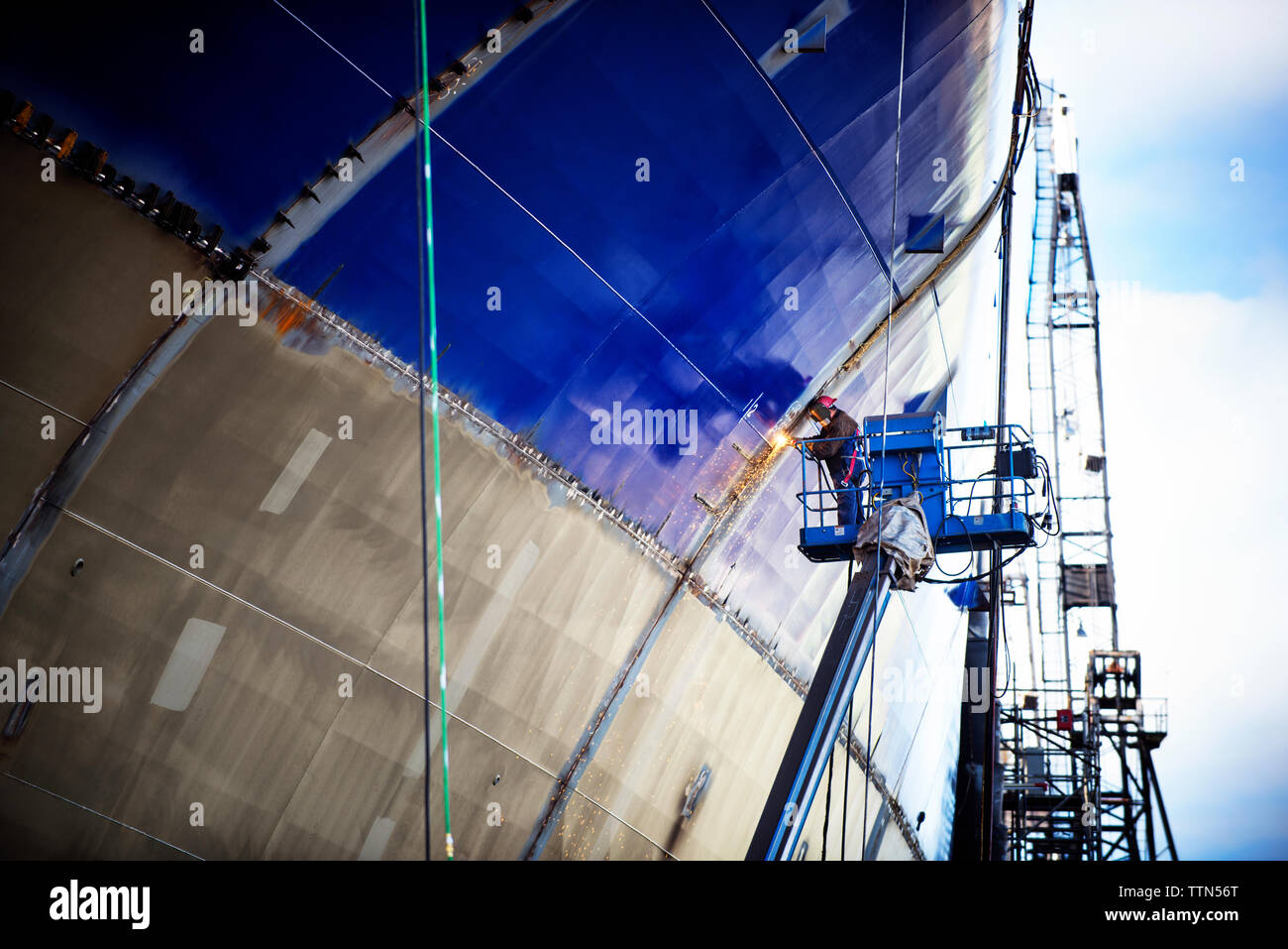 Low angle view of worker welding ship at industry Stock Photo
