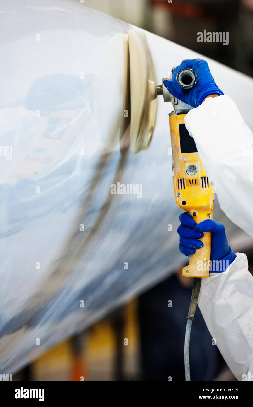 Cropped image of worker using sander on airplane wing at industry Stock Photo