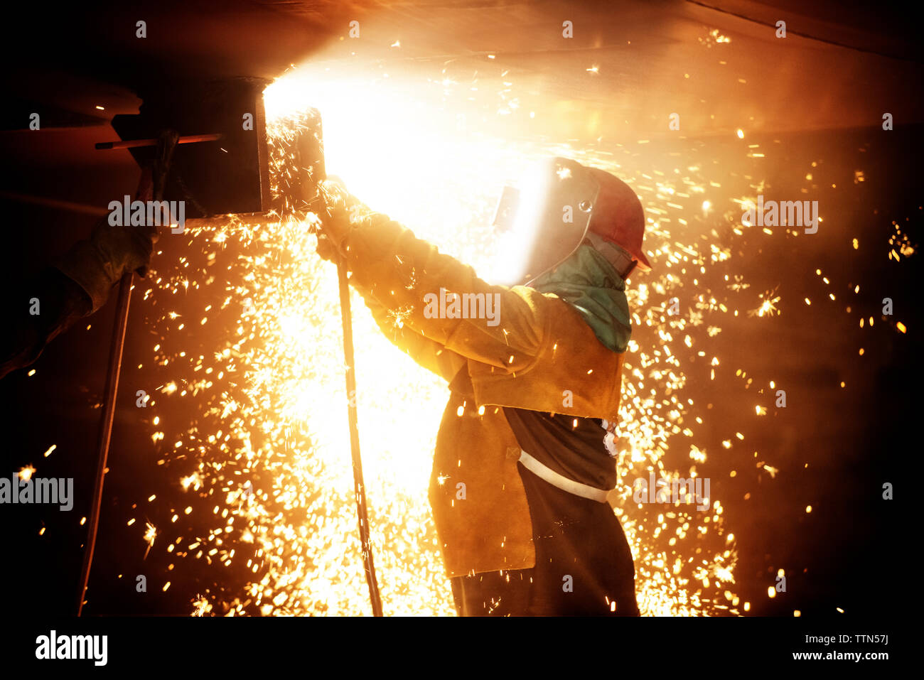 Side view of worker welding airplane wing at industry Stock Photo