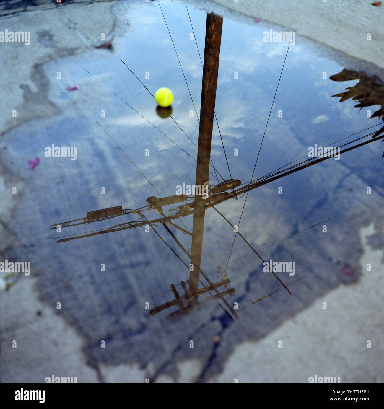High angle view of ball and electricity pylon reflection in puddle on street Stock Photo