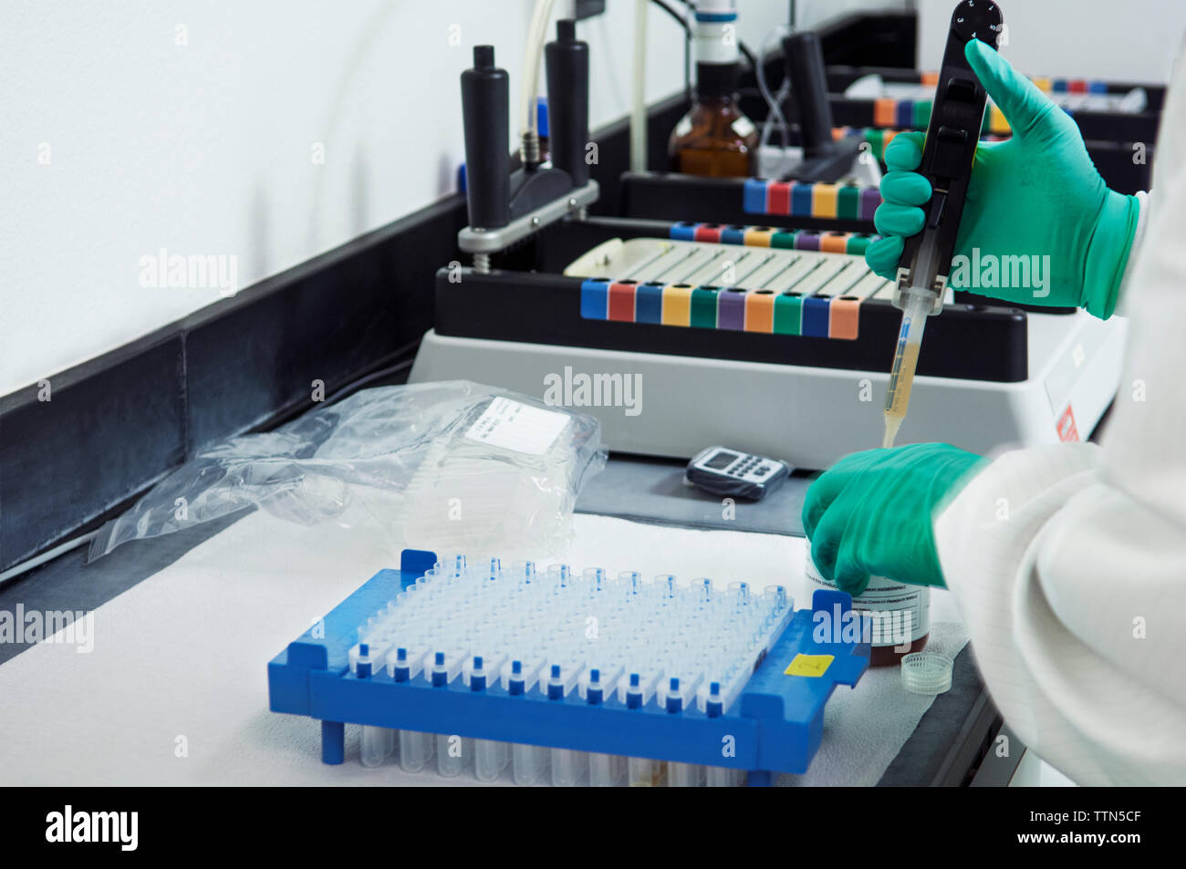 Cropped image of scientist pipetting sample into container in laboratory Stock Photo