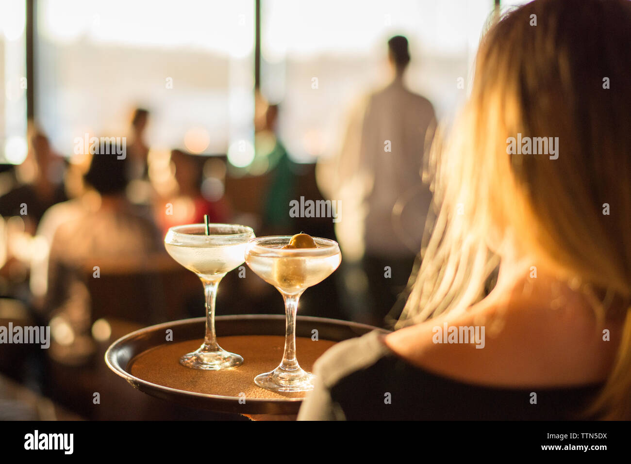 Rear view of waitress holding drinks in tray at restaurant Stock Photo