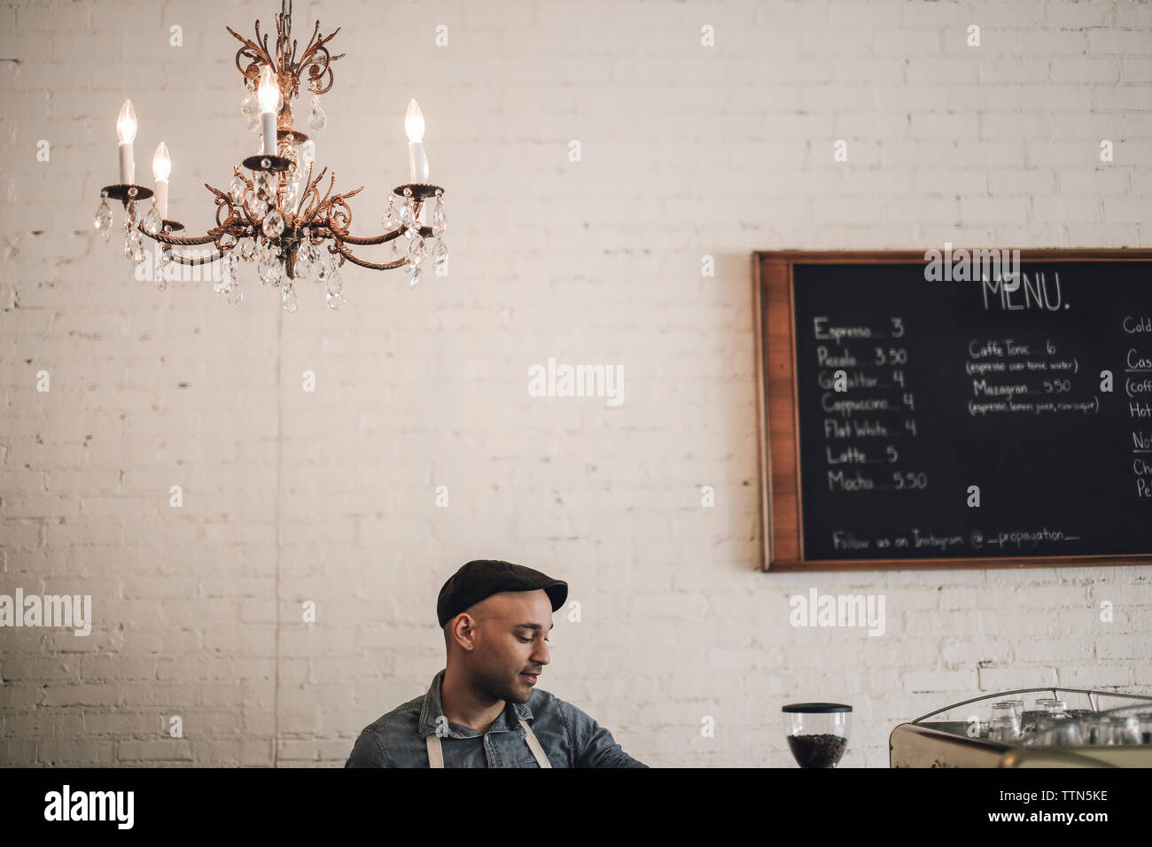 Male owner standing against wall in cafe Stock Photo
