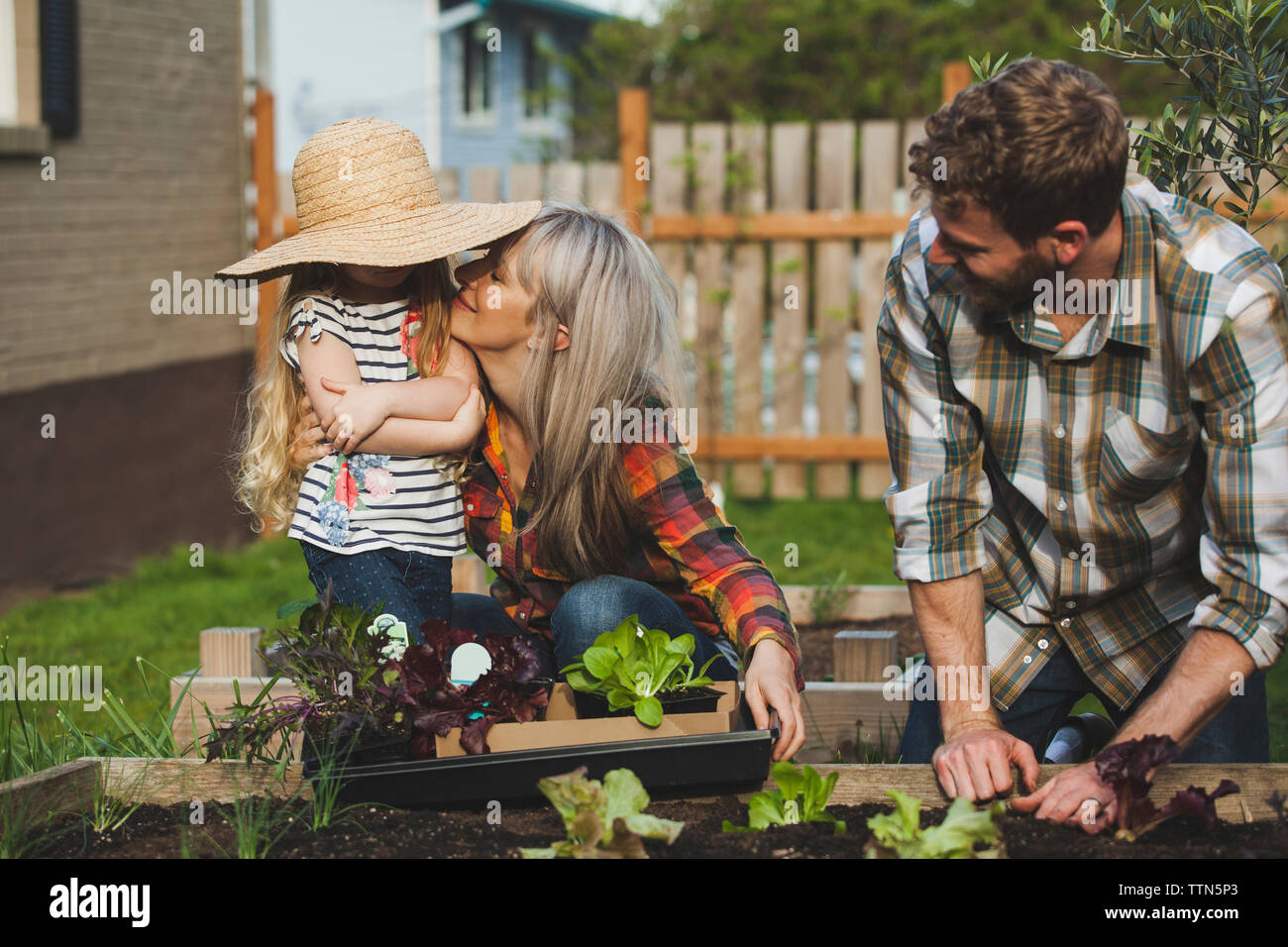 Man looking wife and daughter while gardening at backyard Stock Photo