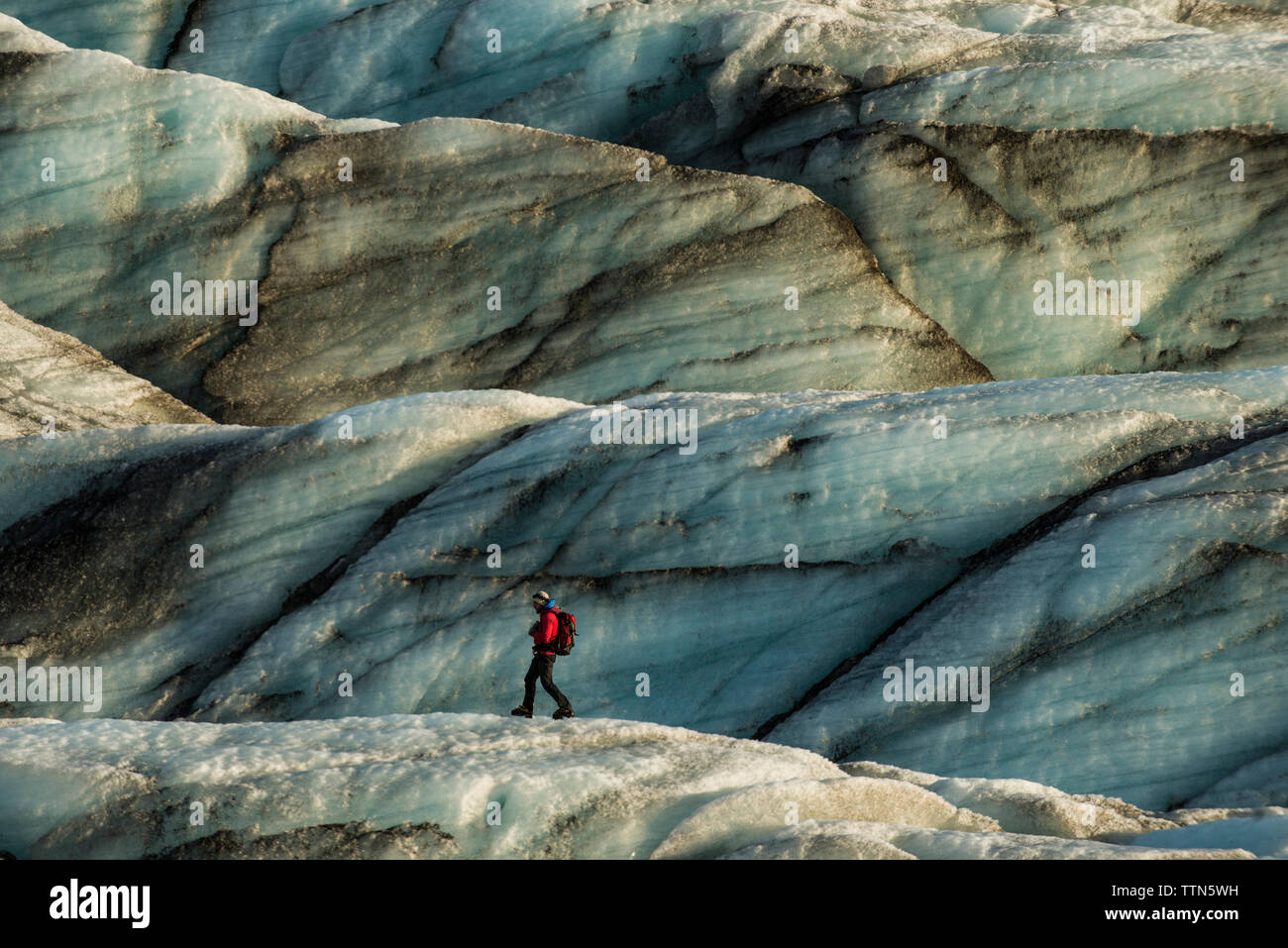 Side view of male backpacker walking on rock formation Stock Photo