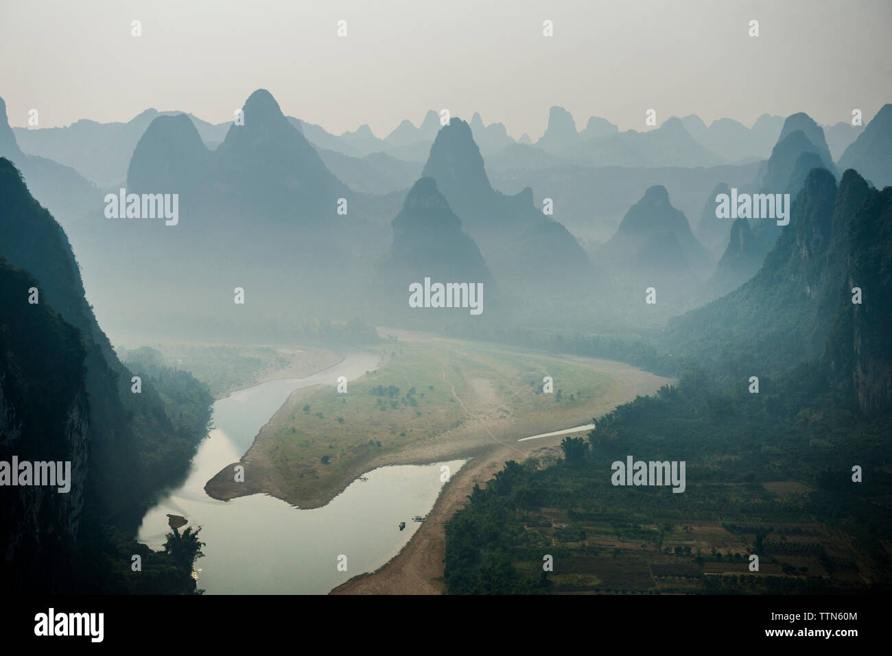 River flowing against mountain during foggy weather Stock Photo