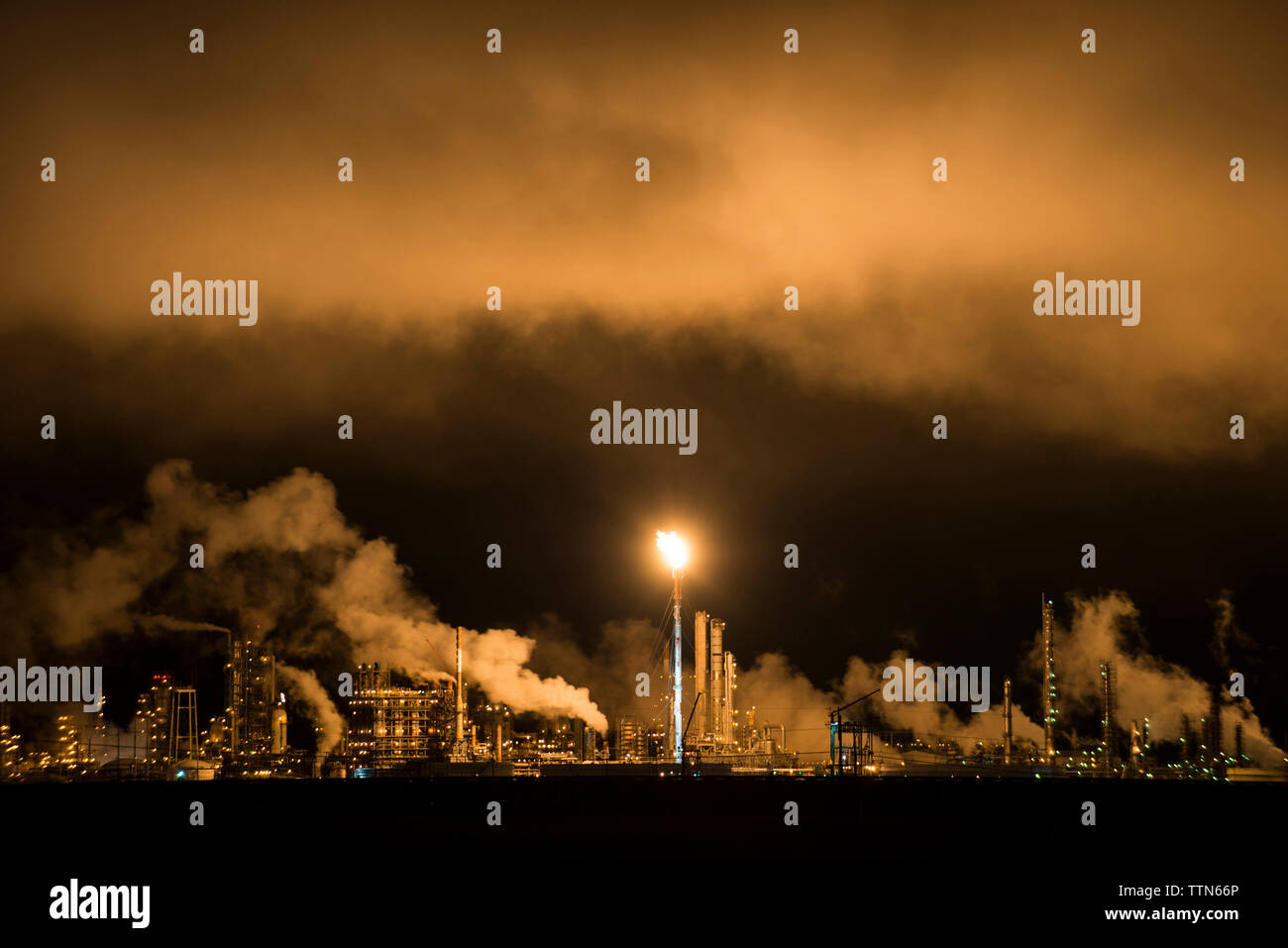 Smoke emitting from factory in sky at night Stock Photo