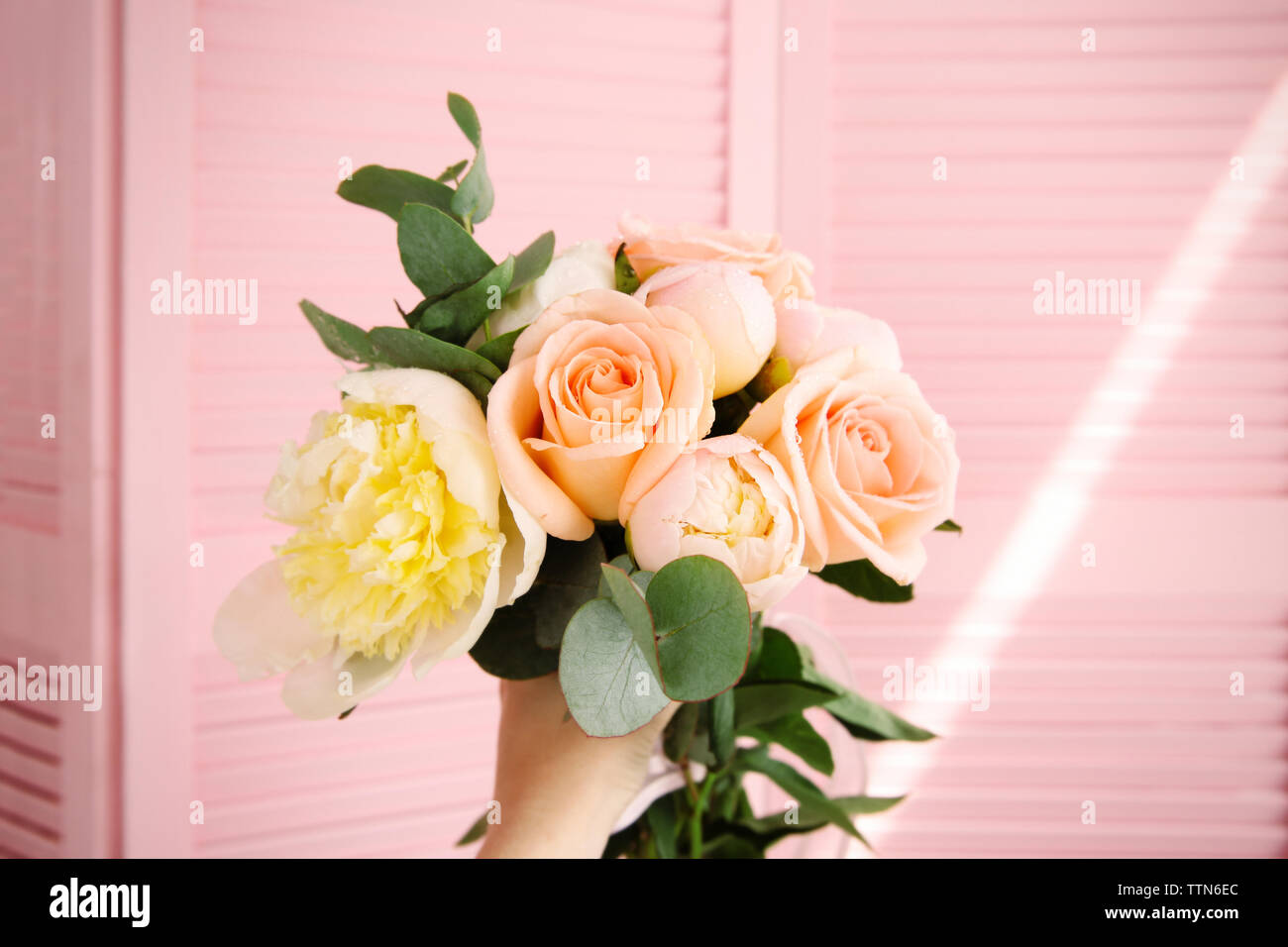 Hand holding bouquet of flowers on pink screen background Stock Photo