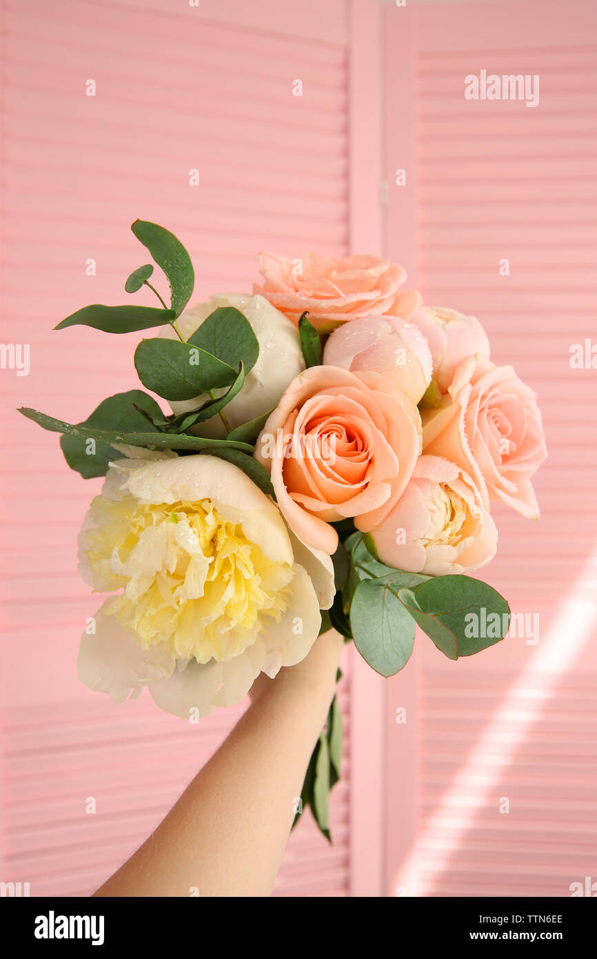 Hand holding bouquet of flowers on pink screen background Stock Photo