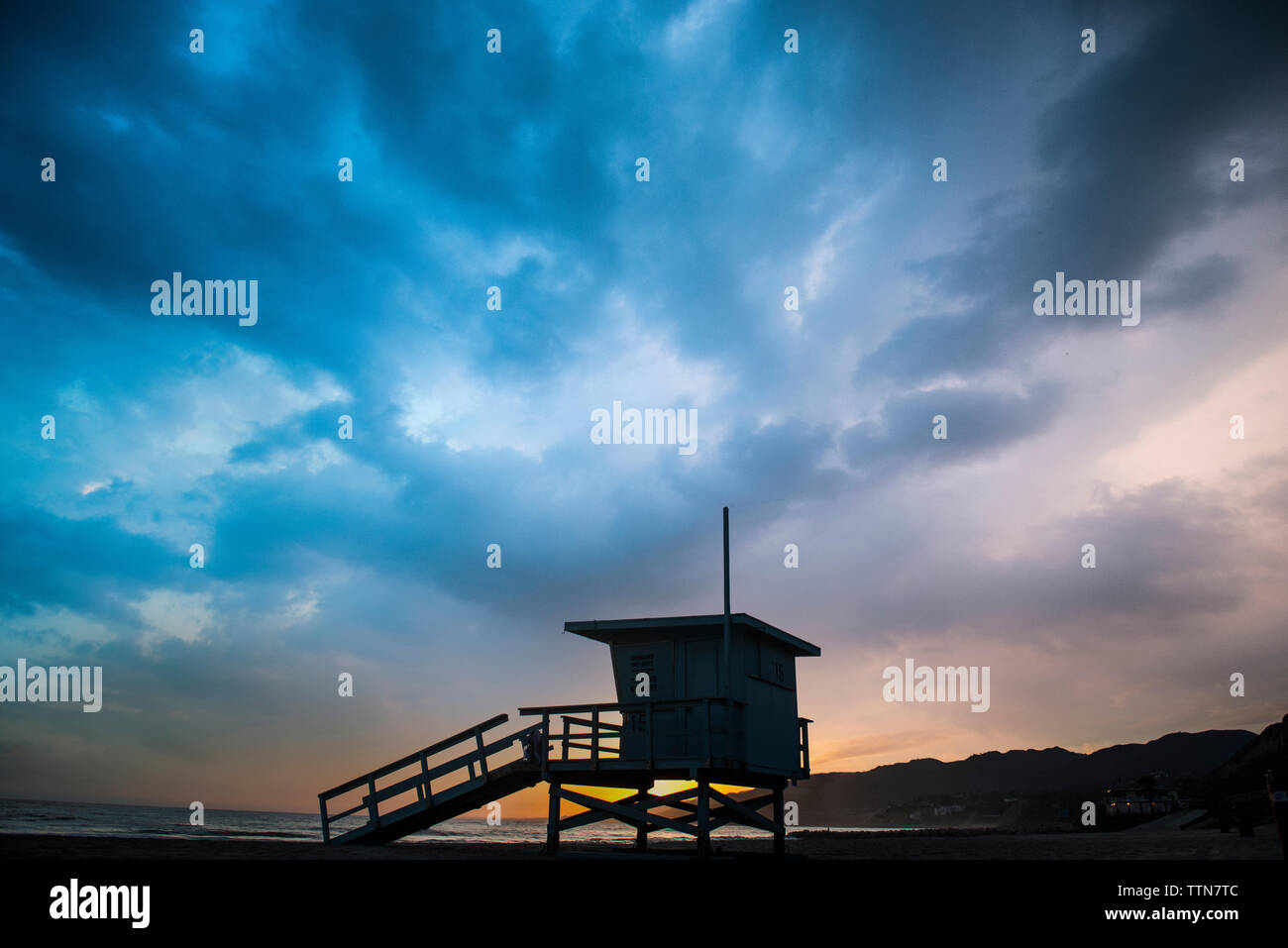 Silhouette lifeguard hut on sand against cloudy sky at Venice beach Stock Photo