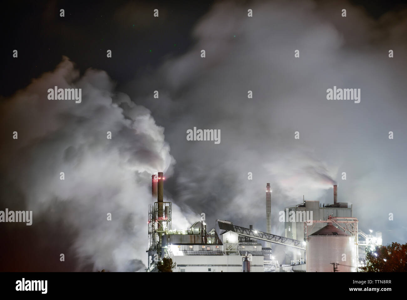 Smoke emitting from factory at night Stock Photo