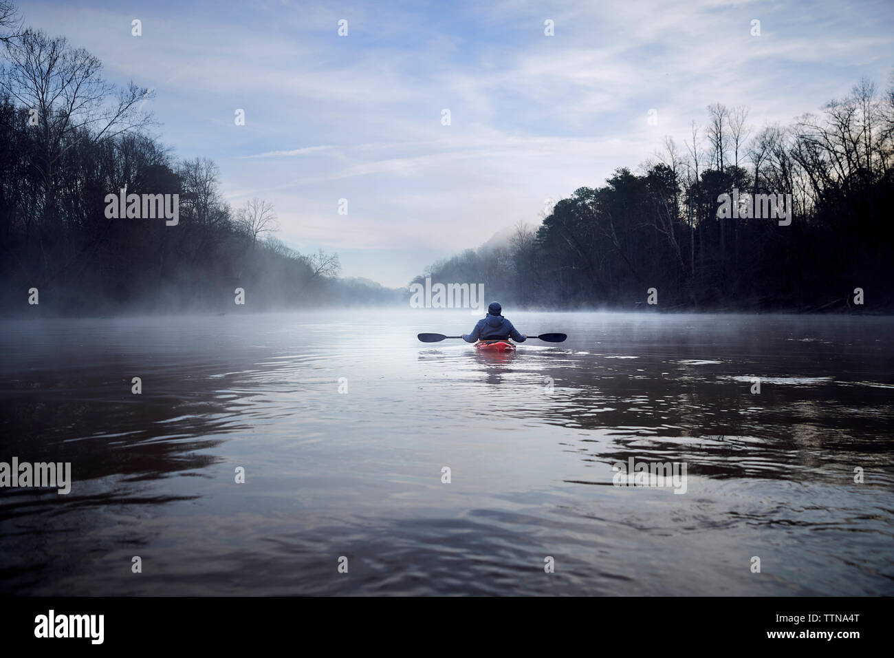 Rear view of man kayaking on Chattahoochee River amidst bare trees