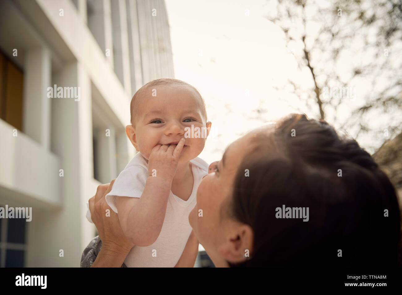 Mother picking up cute daughter against building in city Stock Photo