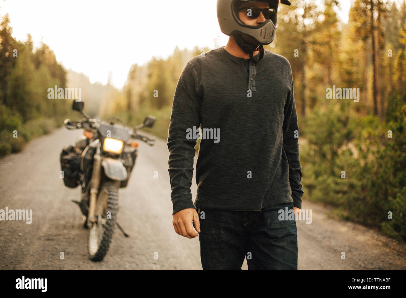 Biker wearing crash helmet while walking on dirt road Stock Photo Alamy