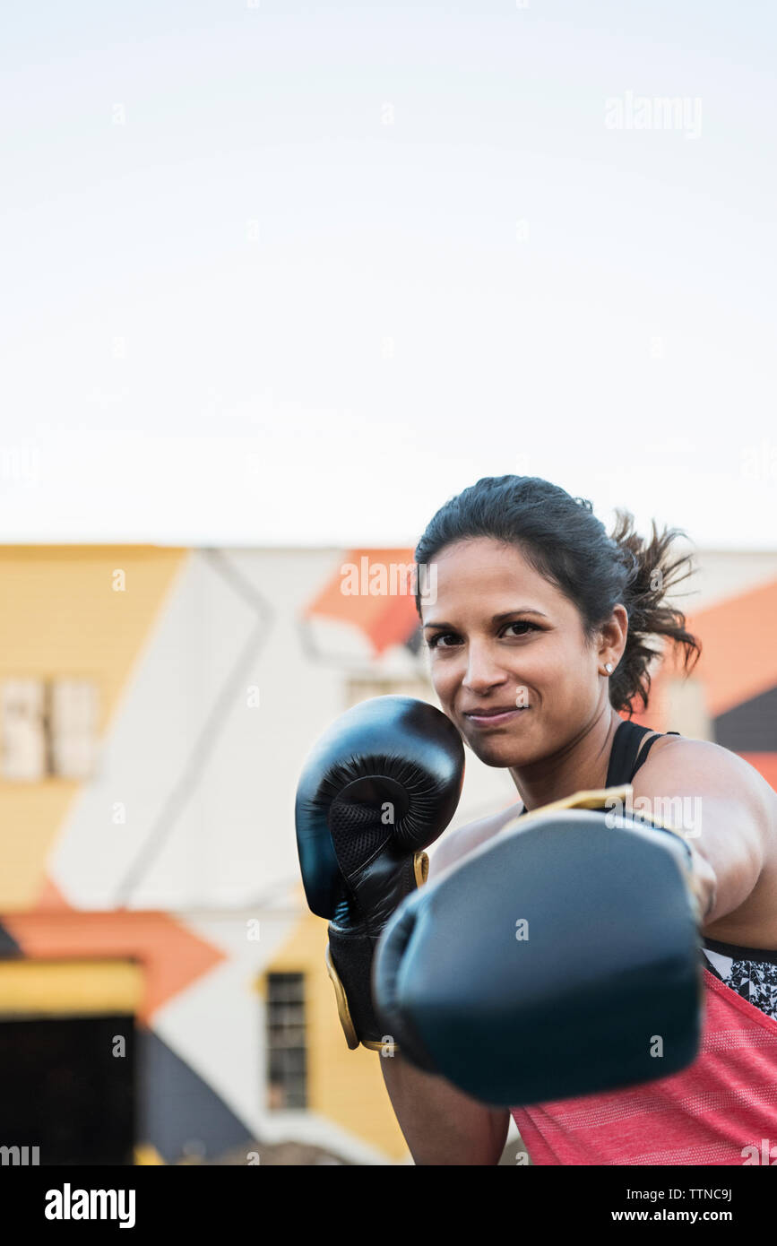 Portrait of confident female boxer outside gym against clear sky Stock Photo