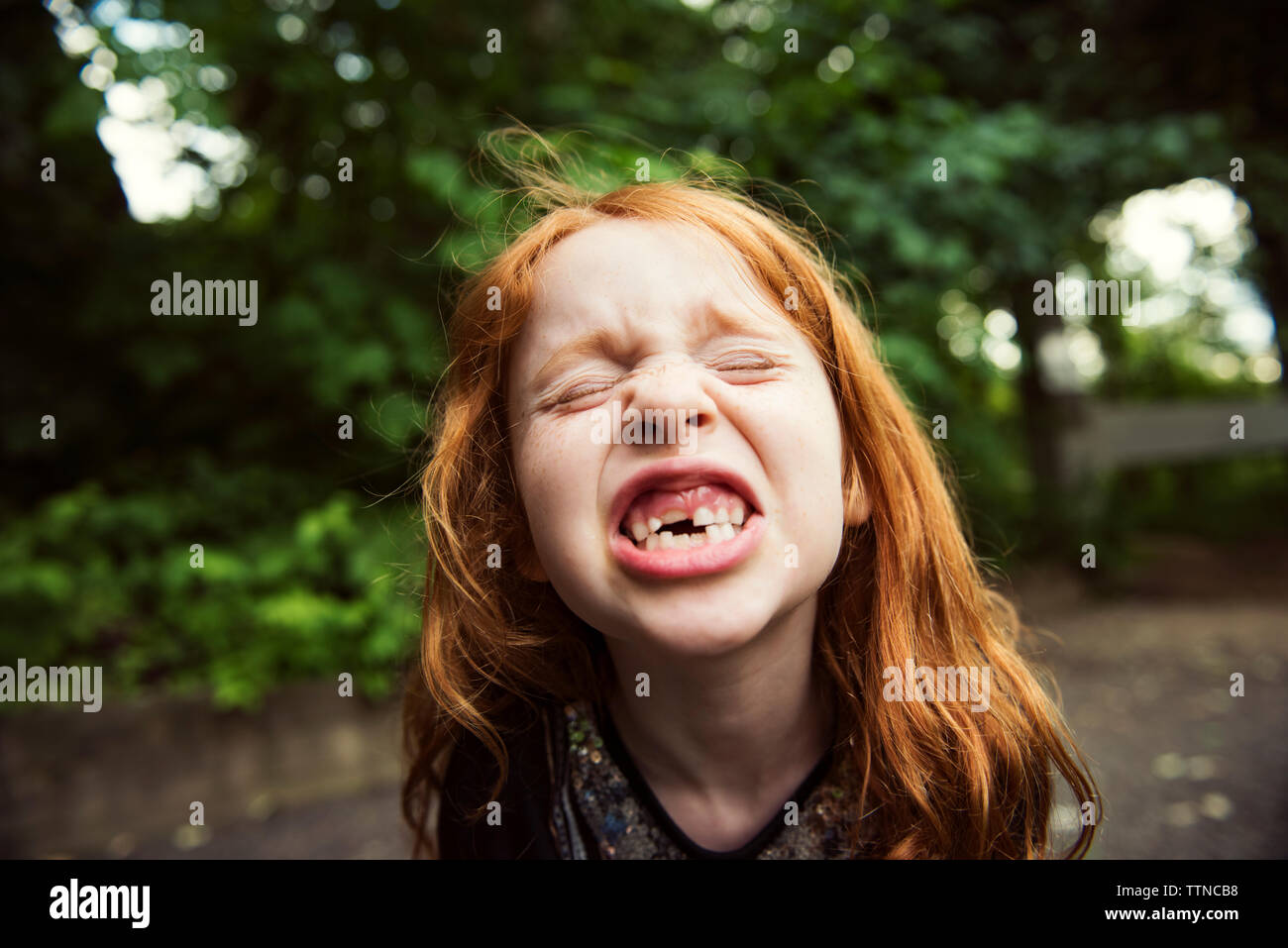 Close-up of girl clenching teeth at park Stock Photo