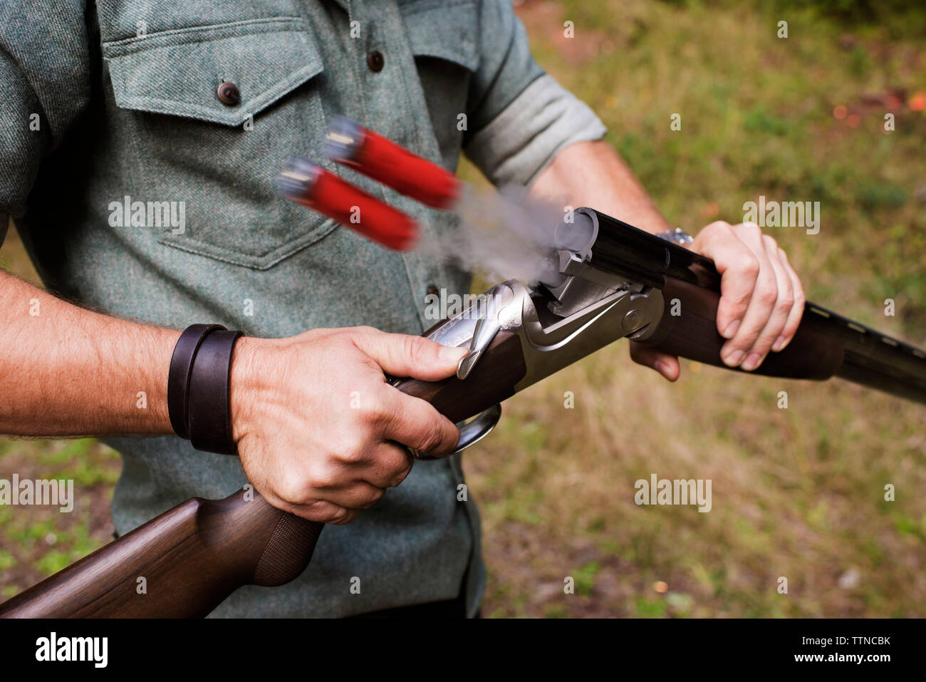 Midsection of hunter with shotgun at field Stock Photo
