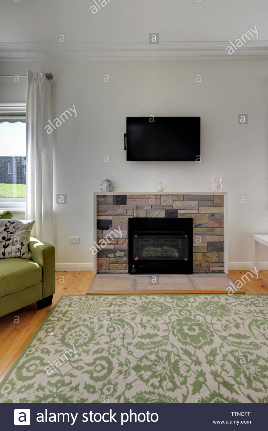 Television Set On Wall Above Fireplace In Modern Living Room Stock