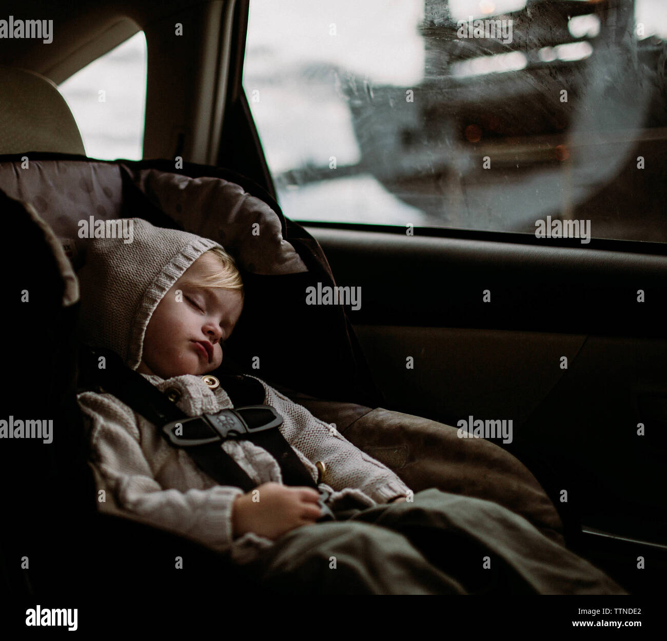 Toddler sleeping in carseat in back of car Stock Photo