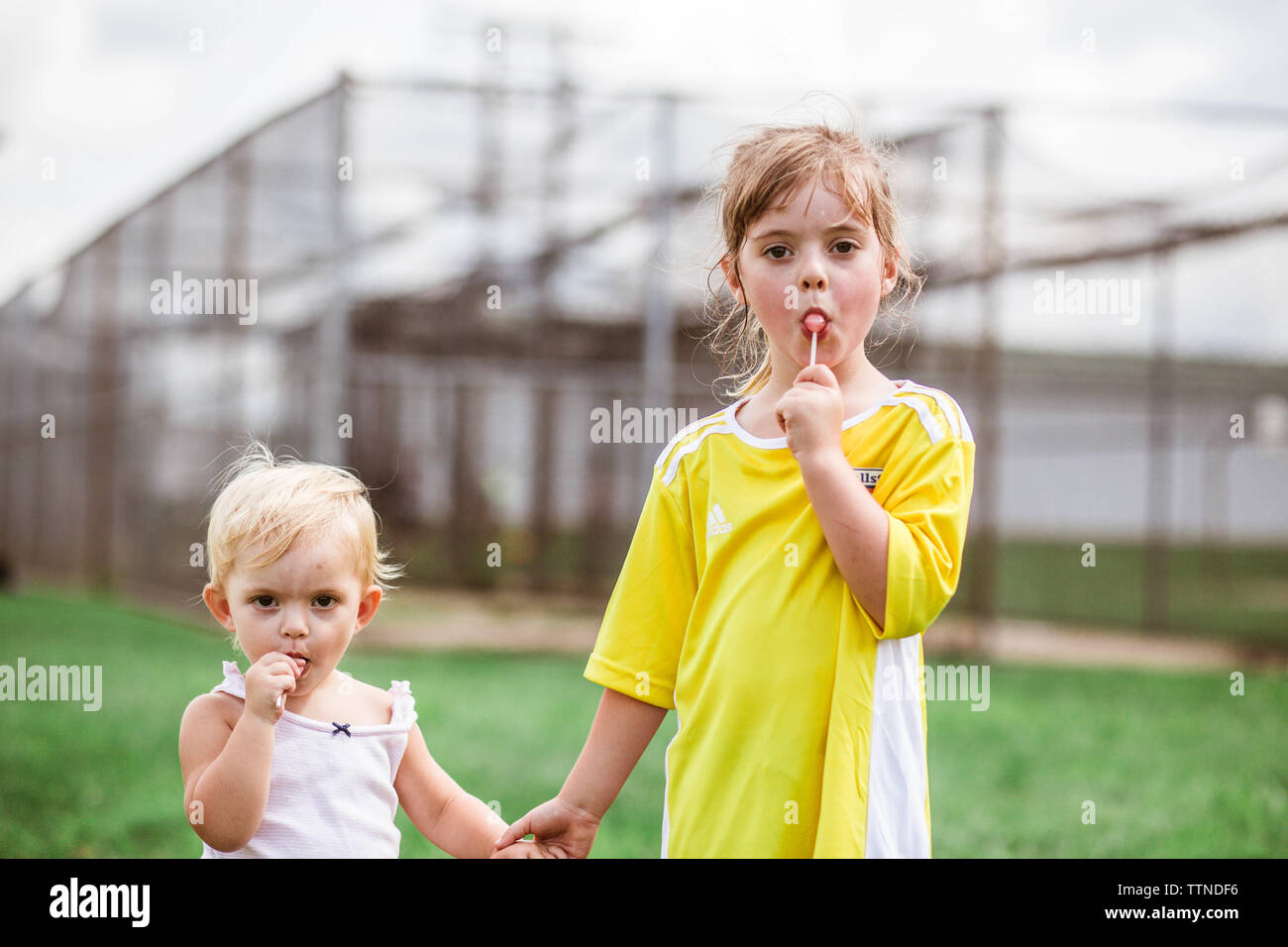 Fierce sisters holding hands with lollipops after soccer game in MD Stock Photo