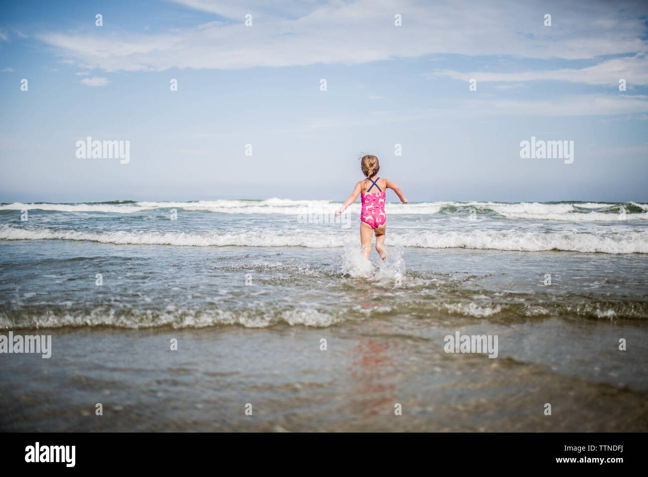 5 year old girl running into ocean waves Stock Photo