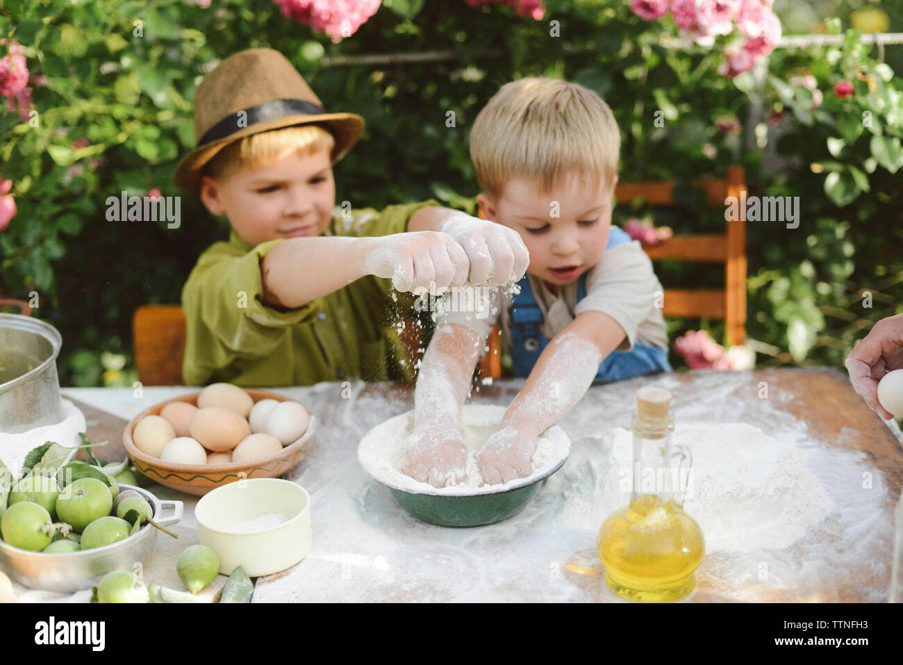 High angle view of brothers preparing food on table in yard Stock Photo