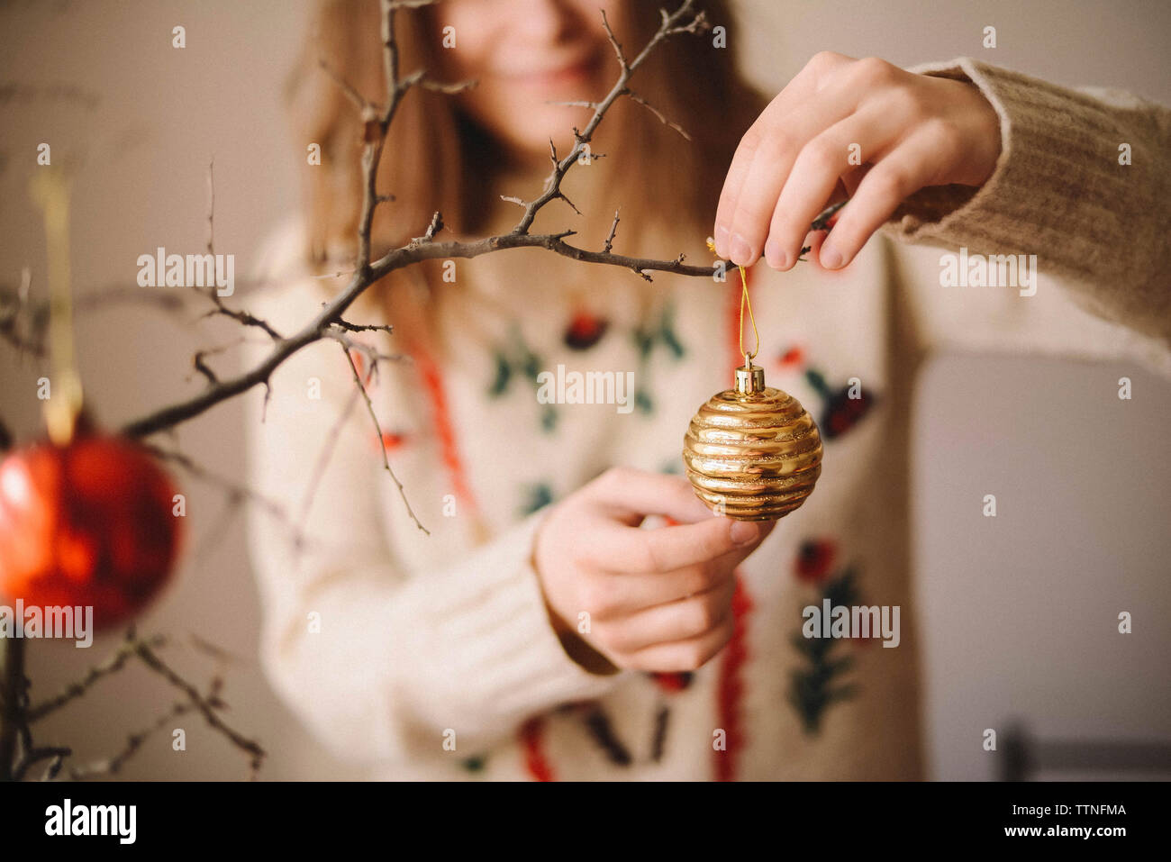 Midsection of woman hanging bauble on twig during christmas at home Stock Photo
